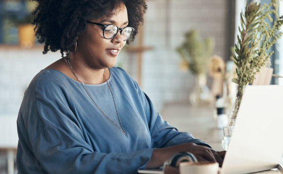 A woman works at her computer in a cafe.