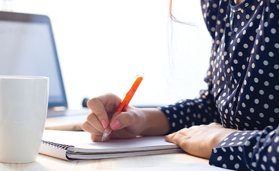 Woman taking notes next to a computer