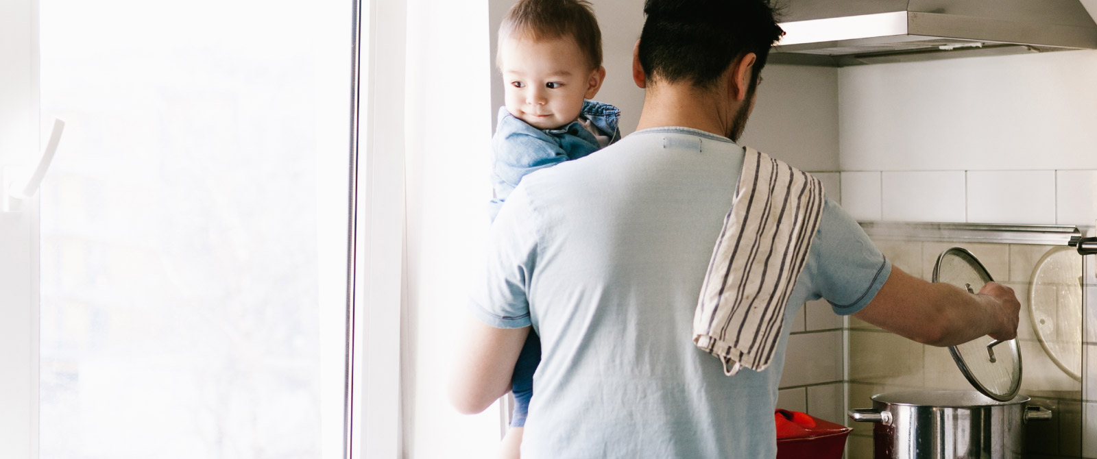 Father checking dinner with his son in his arms.