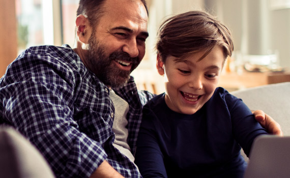 Father and son joyfully explore through a tablet.