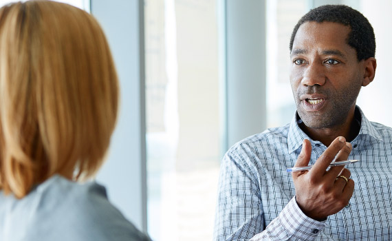 Two business professionals are having a conversation using hand gestures.