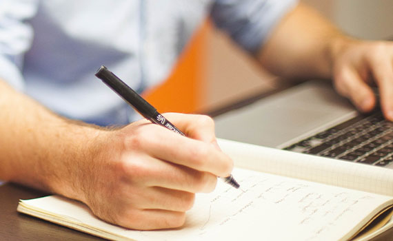 Person on computer taking notes on notepad